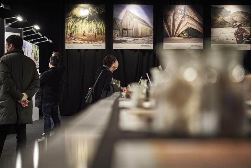 eine reihe von menschen, die vor einer bilderausstellung auf der architect@work 2023 in düsseldorf stehen.