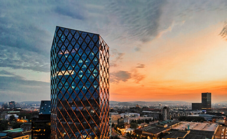 Archicad 27 Signature Gebäude: ein moderner Wolkenkratzer bei Sonnenuntergang in einer stadt.