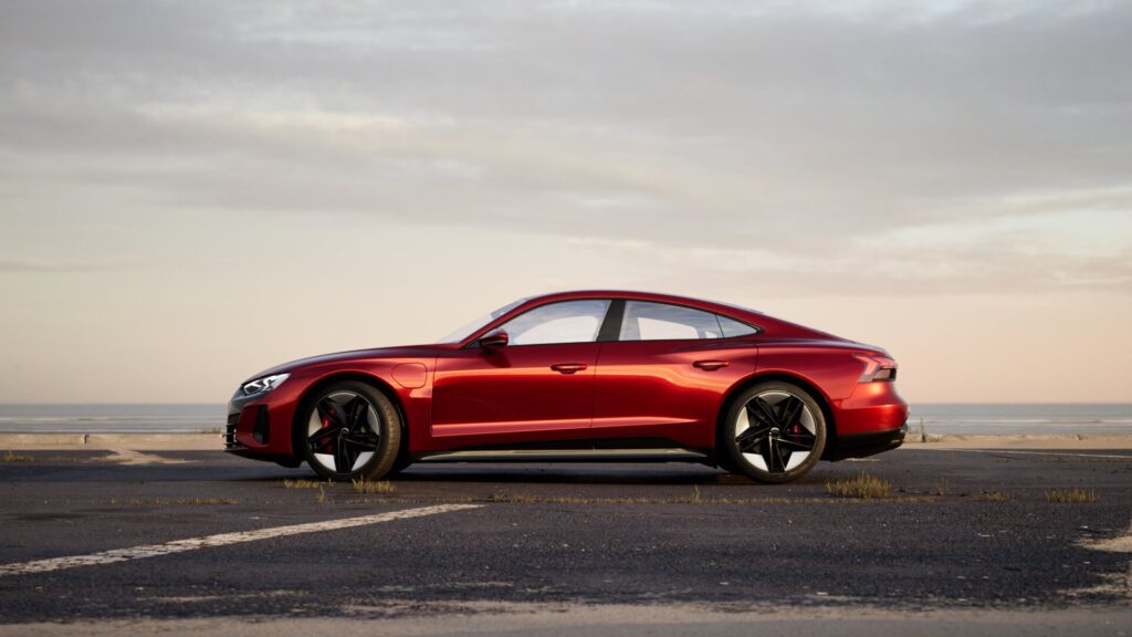 der rote audi e tron concept ist verfügbar und am strand geparkt.