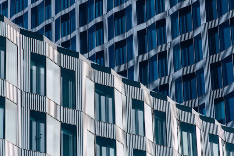 Nahaufnahme einer modernen Gebäudefassade mit sich wiederholenden geometrischen Mustern, vertikalen Linien und Glasfenstern, die das Licht reflektieren - ein beeindruckendes Design, das bei den Architizer A+ Awards 2025 ausgezeichnet wurde.