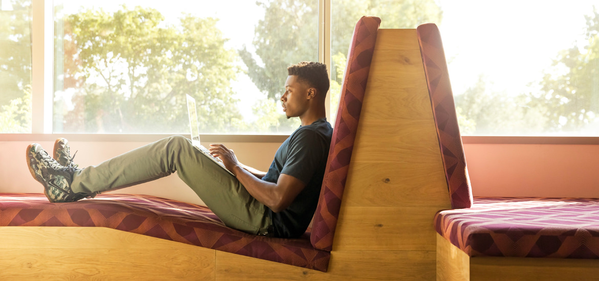 Ein Mann sitzt mit einem Laptop auf einer Bank und ist in das ARCHICAD-Tutor-Programm vertieft.