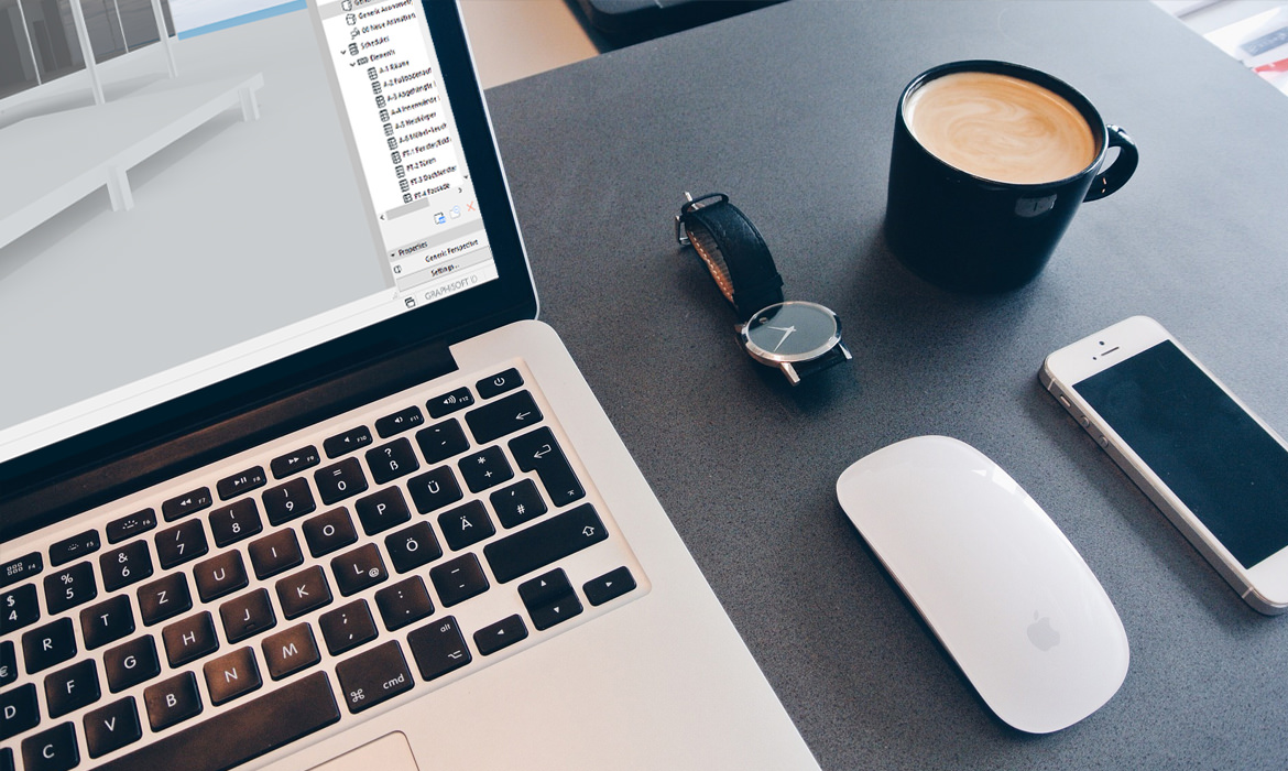 Eine Kaffeetasse steht neben einem Laptop auf einem Schreibtisch.