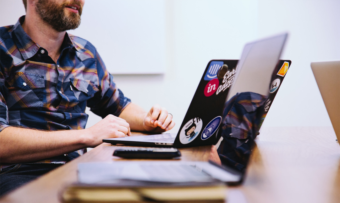 Ein Bildungsmanager in Wien sitzt mit einem Laptop an einem Schreibtisch.