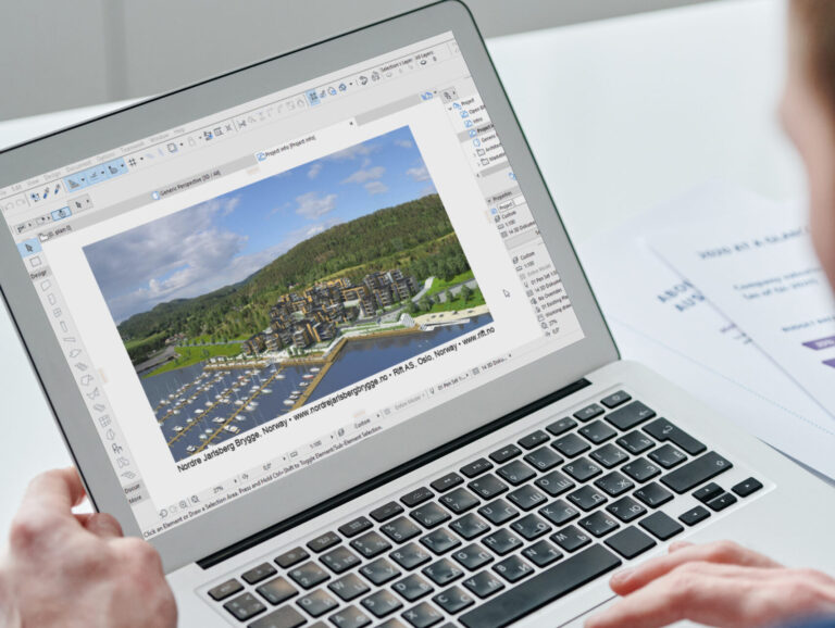 Eine Person verwendet einen Laptop, um einen Archicad-Architekturentwurf einer Seeufersiedlung mit Gebäuden, Straßen und Grünflächen anzuzeigen.